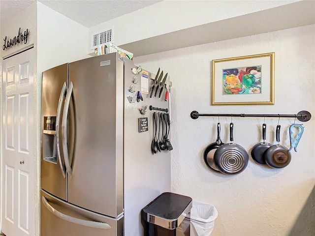 kitchen with a textured ceiling and stainless steel refrigerator with ice dispenser