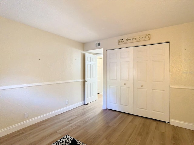 unfurnished bedroom featuring wood-type flooring and a closet