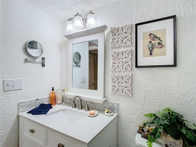 bathroom featuring vanity, decorative backsplash, and toilet