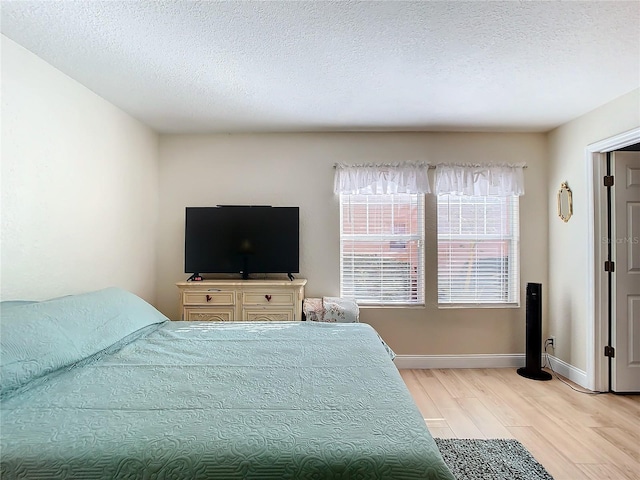 bedroom with light hardwood / wood-style flooring and a textured ceiling