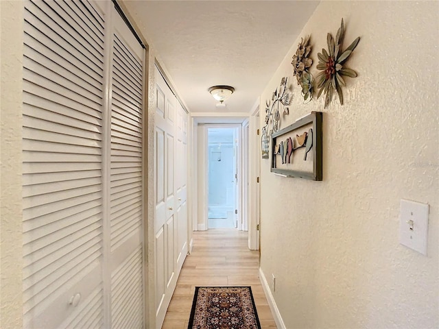 corridor featuring a textured ceiling and light wood-type flooring