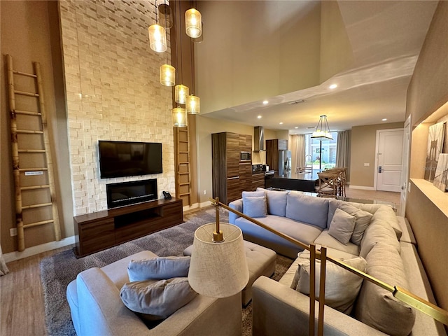 living room featuring a high ceiling, wood-type flooring, and a fireplace