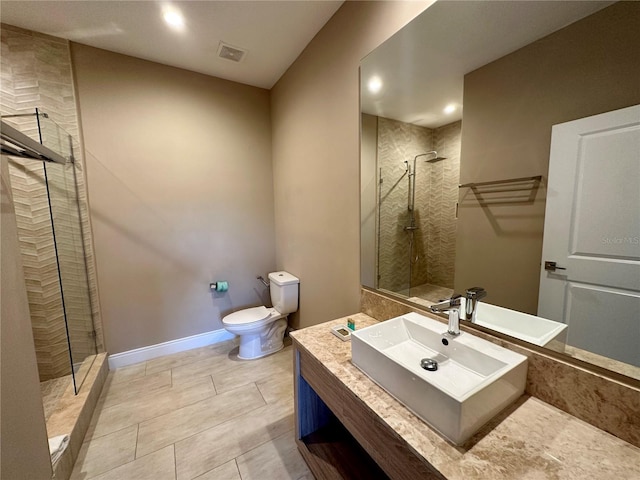 bathroom with toilet, tile floors, a tile shower, and vanity