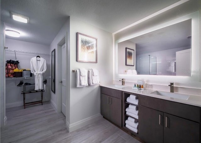 bathroom featuring vanity, a textured ceiling, hardwood / wood-style flooring, and a shower with shower door