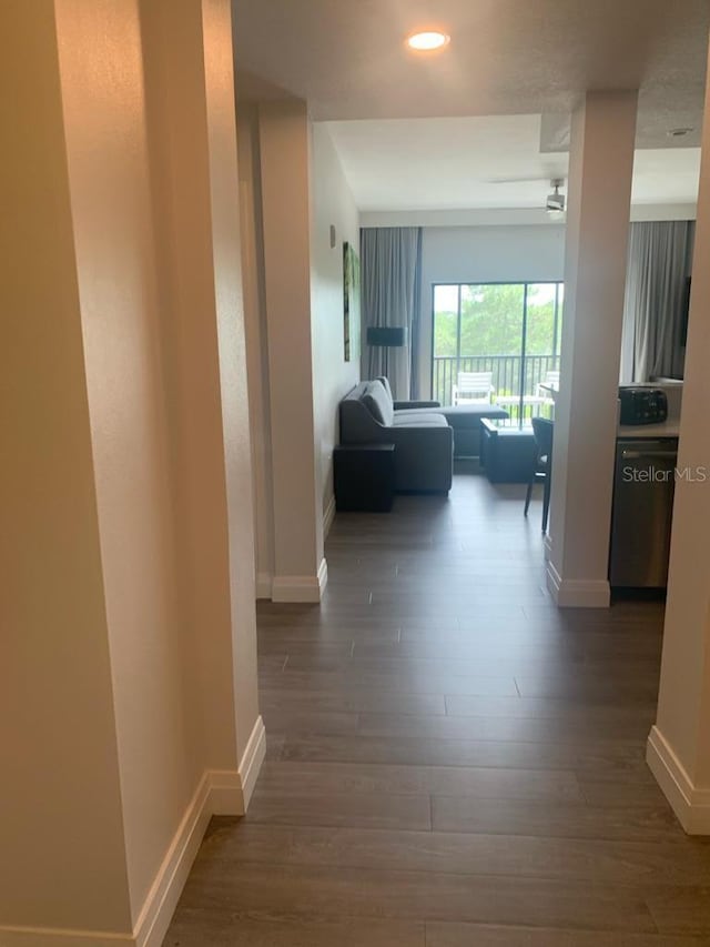 hallway featuring recessed lighting, dark wood-style flooring, and baseboards