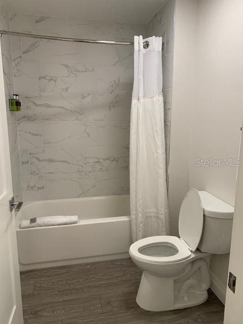 bathroom with shower / bath combo with shower curtain, baseboards, toilet, and wood finished floors