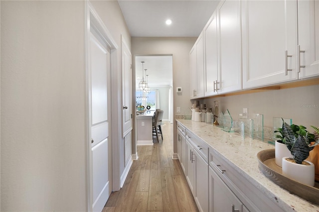 kitchen featuring white cabinets, light stone countertops, and light hardwood / wood-style floors