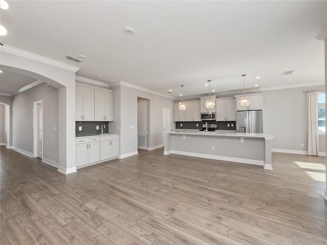 kitchen featuring tasteful backsplash, hanging light fixtures, appliances with stainless steel finishes, and light wood-type flooring