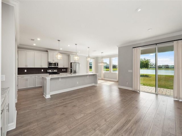 kitchen featuring white cabinets, light hardwood / wood-style floors, a center island with sink, and stainless steel appliances