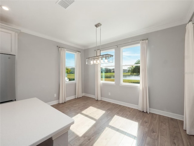 unfurnished dining area with ornamental molding, a notable chandelier, a healthy amount of sunlight, and light wood-type flooring