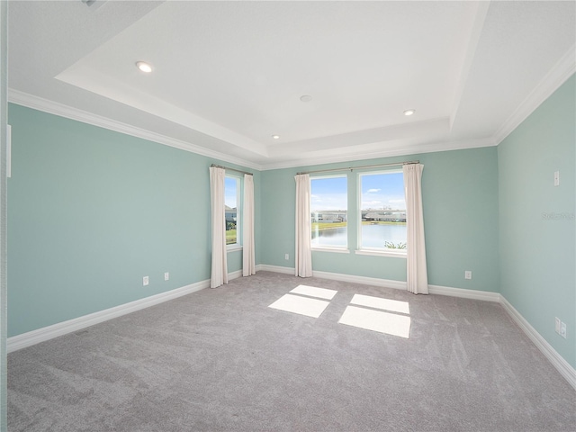 unfurnished room with a water view, a raised ceiling, and ornamental molding