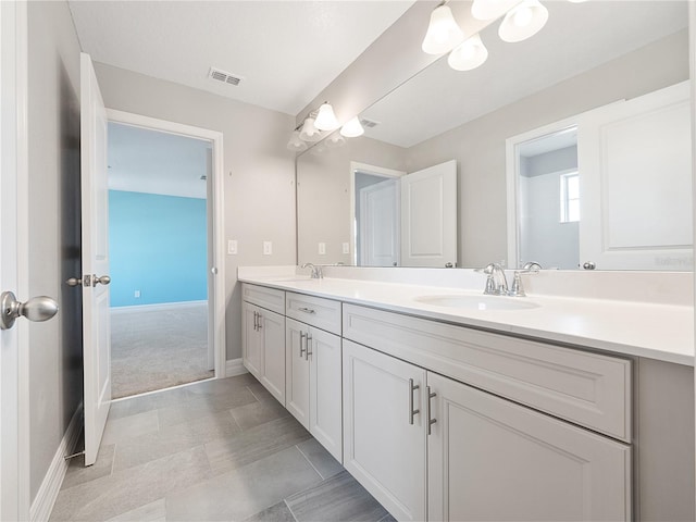 bathroom with tile floors, vanity with extensive cabinet space, and double sink