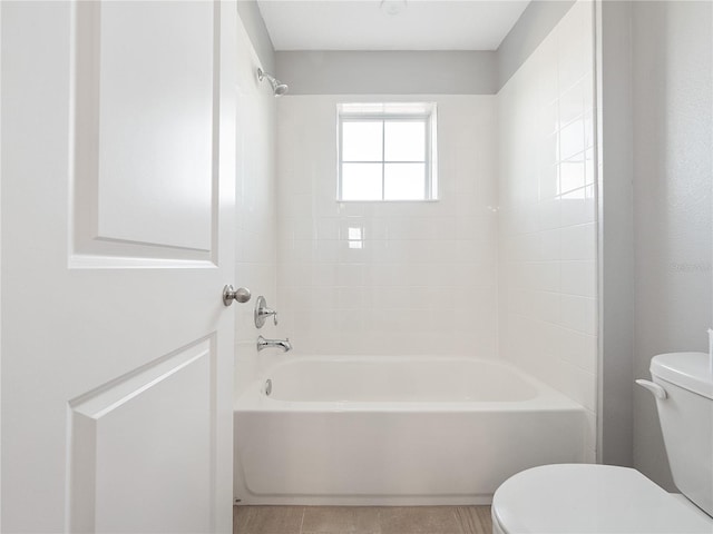 bathroom with toilet, tiled shower / bath, and tile flooring