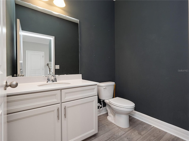 bathroom with toilet, vanity, and hardwood / wood-style flooring