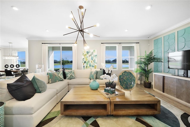 living room with light hardwood / wood-style flooring, a healthy amount of sunlight, ornamental molding, and a notable chandelier