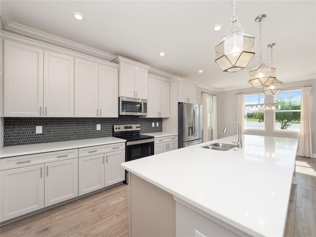 kitchen featuring pendant lighting, sink, appliances with stainless steel finishes, backsplash, and a center island with sink