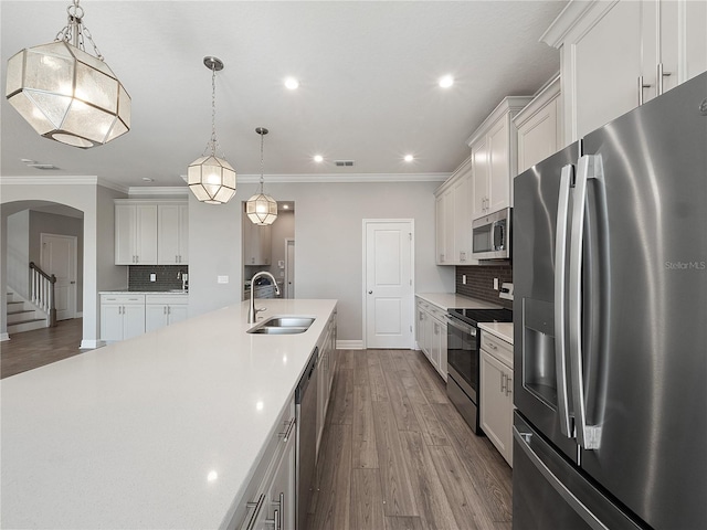 kitchen featuring pendant lighting, backsplash, white cabinetry, and stainless steel appliances