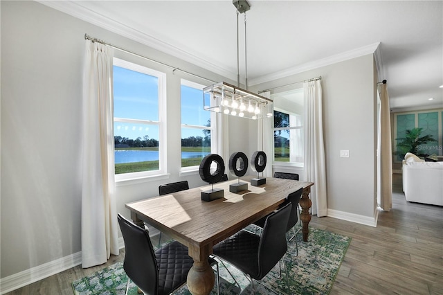 dining room with crown molding, dark hardwood / wood-style floors, a water view, and a chandelier