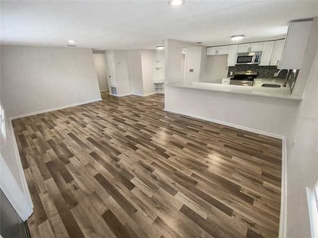 kitchen with backsplash, stainless steel appliances, white cabinetry, and dark hardwood / wood-style flooring