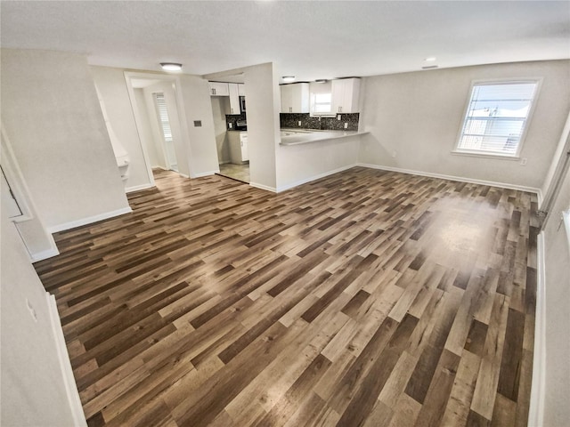 unfurnished living room featuring a textured ceiling and dark hardwood / wood-style floors