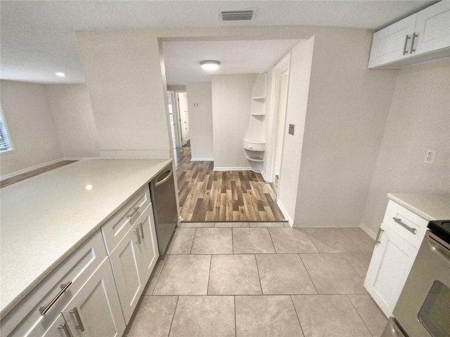 kitchen featuring light tile flooring, dishwasher, electric stove, and white cabinetry