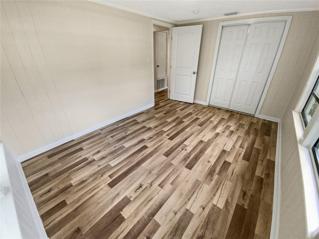 unfurnished bedroom with a closet, light wood-type flooring, and crown molding