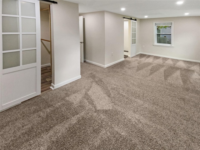 carpeted spare room featuring a barn door