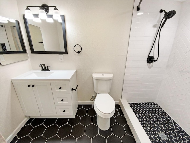 bathroom with tile floors, toilet, vanity, and tiled shower