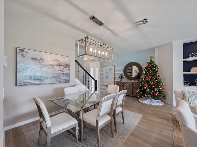 dining area featuring built in features, a notable chandelier, and wood-type flooring