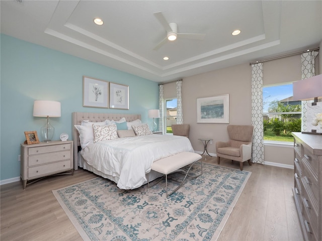 bedroom featuring a raised ceiling, light hardwood / wood-style floors, and ceiling fan