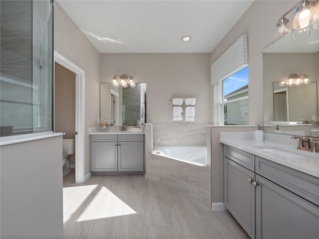 bathroom with a relaxing tiled bath, large vanity, and tile flooring