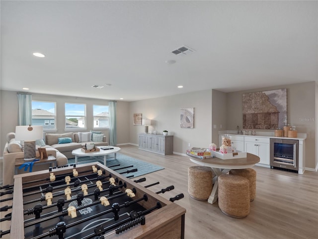 living room featuring wine cooler, light wood-type flooring, and sink