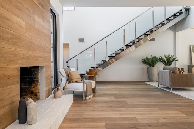 stairway featuring hardwood / wood-style floors, a large fireplace, and a towering ceiling