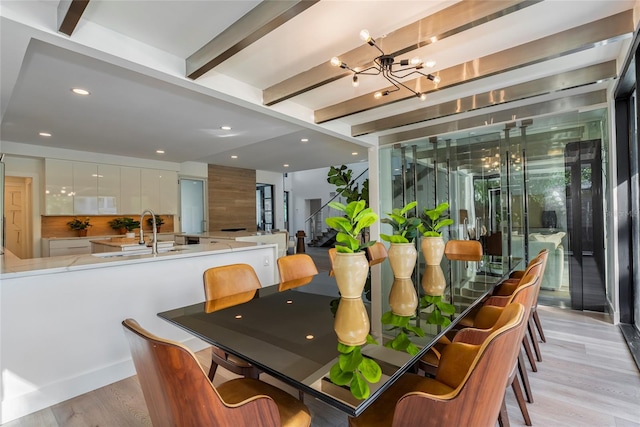 dining room featuring a notable chandelier, beam ceiling, light hardwood / wood-style floors, and sink