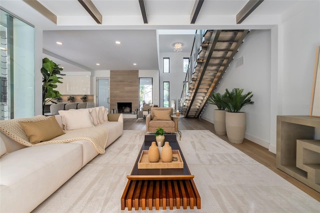 living room featuring beam ceiling, light wood-type flooring, and a tiled fireplace