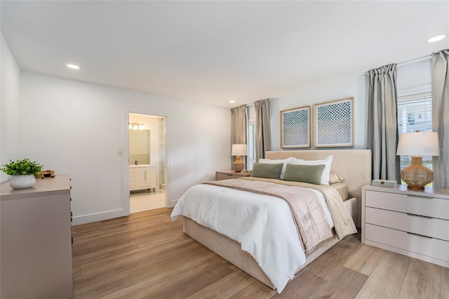 bedroom with ensuite bathroom and light hardwood / wood-style floors