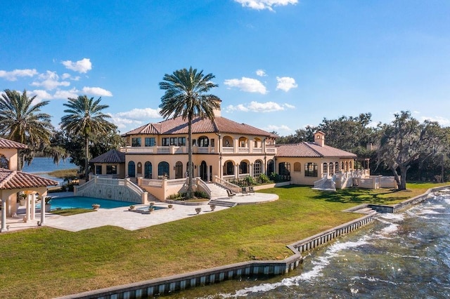 rear view of house with a pool, a yard, and a patio area