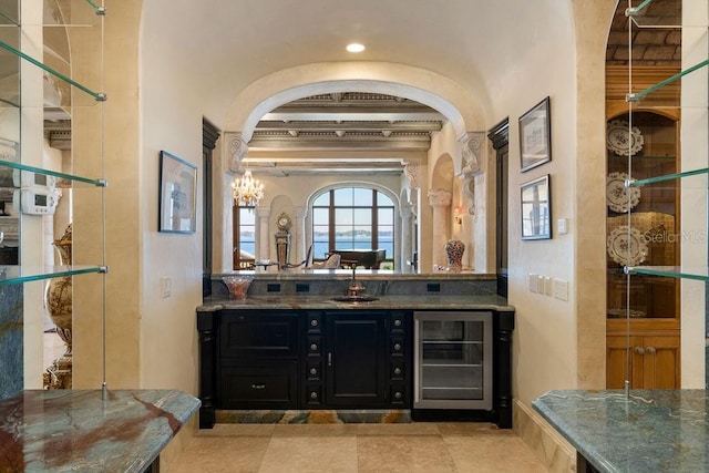 interior space with beverage cooler, light tile floors, sink, and an inviting chandelier