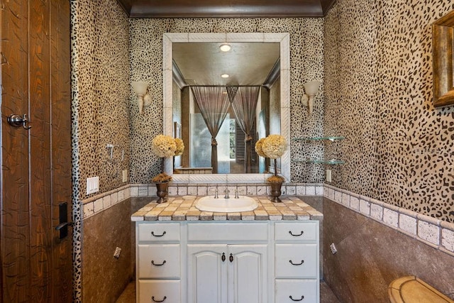 bathroom with vanity, crown molding, and tile walls