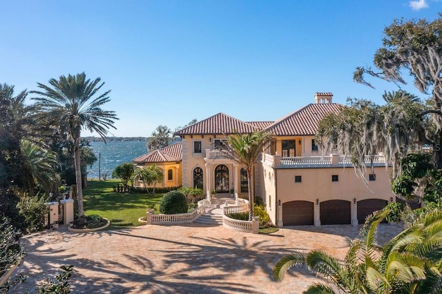 mediterranean / spanish-style house with a water view, a front lawn, and a garage