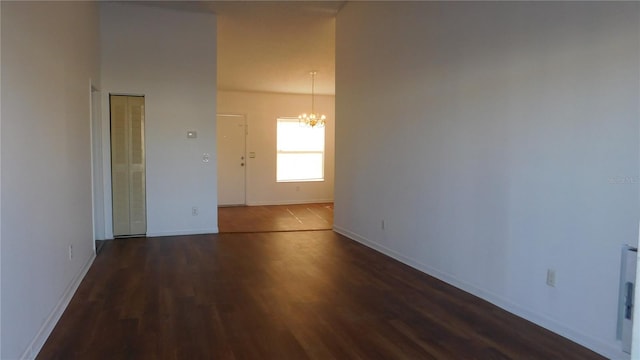 empty room with a chandelier and dark hardwood / wood-style flooring