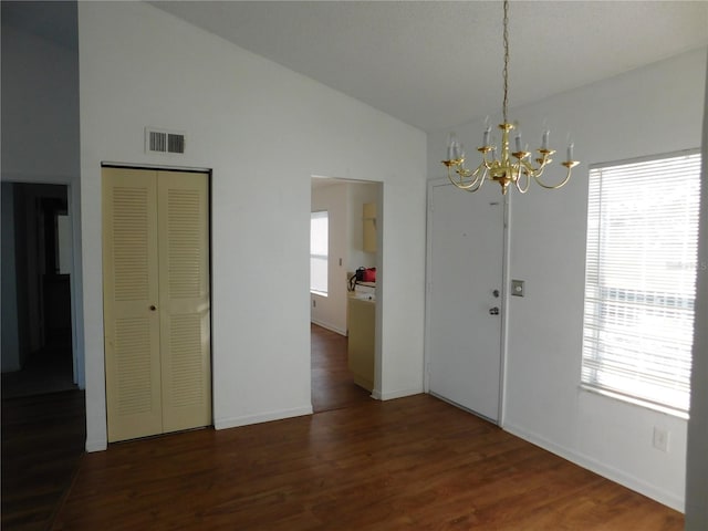 unfurnished dining area featuring an inviting chandelier, dark hardwood / wood-style flooring, vaulted ceiling, and a wealth of natural light