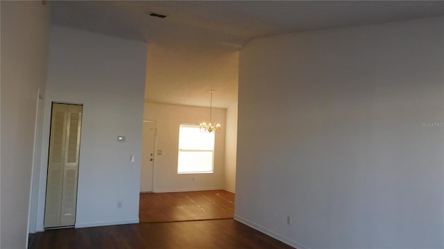 empty room with an inviting chandelier and dark hardwood / wood-style floors