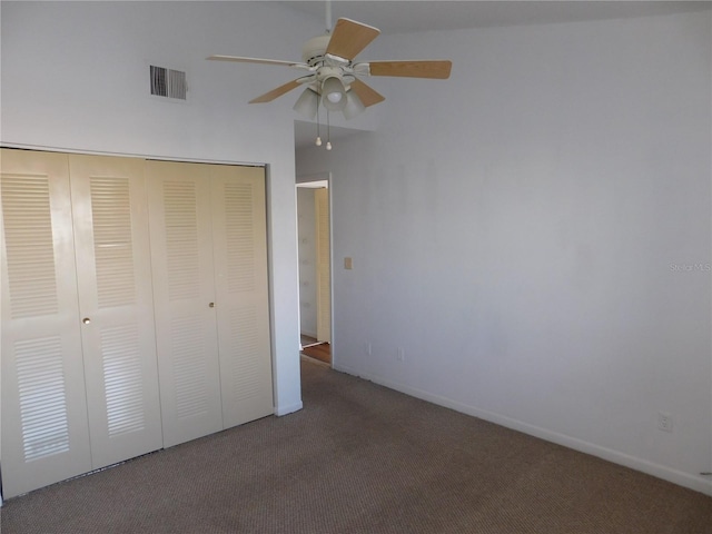 unfurnished bedroom featuring a closet, dark colored carpet, and ceiling fan