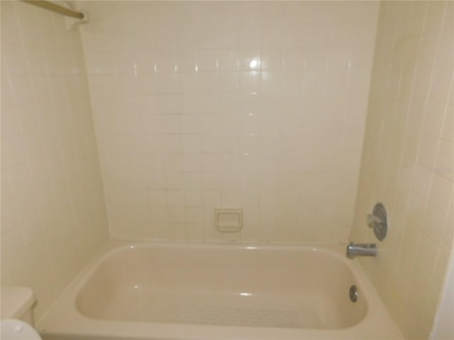 bathroom featuring tiled shower / bath and toilet