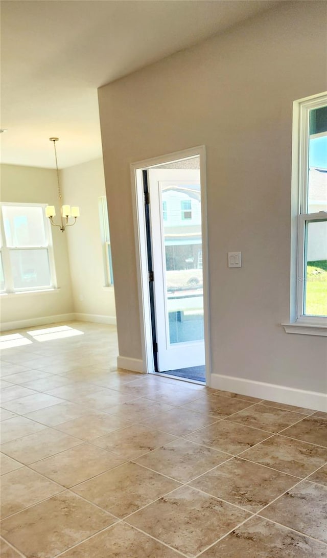 unfurnished room with a chandelier, a healthy amount of sunlight, and light tile patterned flooring