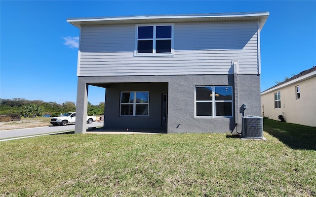 back of property featuring central AC unit and a lawn