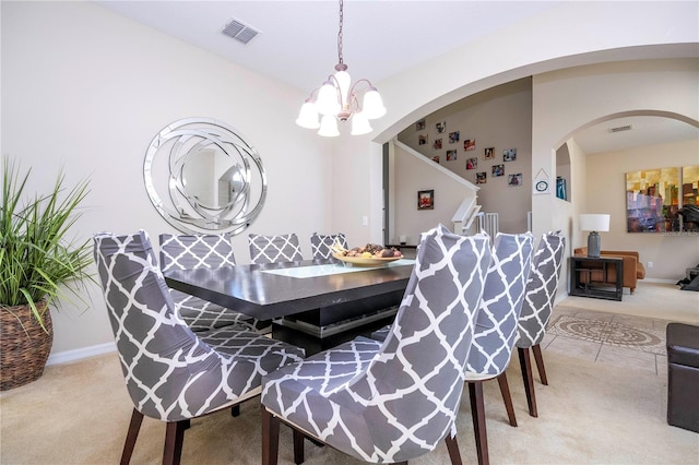 dining space with light carpet and a chandelier