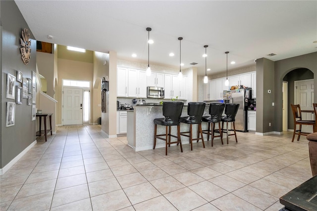 kitchen featuring white cabinets, a kitchen breakfast bar, light tile floors, and appliances with stainless steel finishes