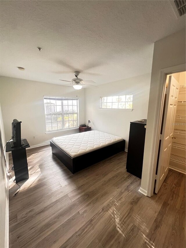 bedroom featuring dark wood-style floors, baseboards, and a textured ceiling